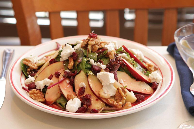 Salad with apple slices, crumbled cheese and walnuts