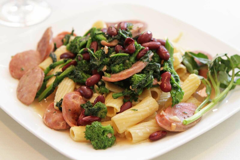 Rigatoni pasta with sausage medallions and spinach